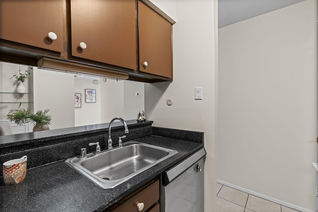 kitchen with a sink, dark countertops, light tile patterned floors, and dishwasher