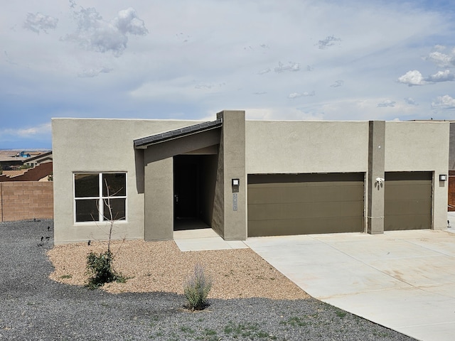 3406 Falkirk Rd NE, Rio Rancho, NM 87144 - pueblo-style home featuring an attached garage, stucco siding, and driveway