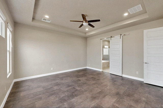3406 Falkirk Rd NE, Rio Rancho, NM 87144 - unfurnished bedroom with a tray ceiling, a barn door, baseboards, recessed lighting, and connected bathroom