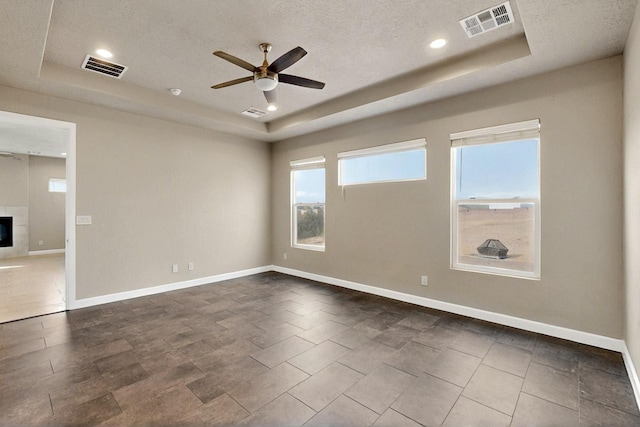 3406 Falkirk Rd NE, Rio Rancho, NM 87144 - empty room with a raised ceiling, a ceiling fan, baseboards, a textured ceiling, and a tiled fireplace
