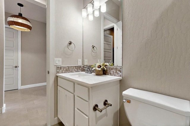 3406 Falkirk Rd NE, Rio Rancho, NM 87144 - half bathroom featuring toilet, vanity, a textured wall, baseboards, and backsplash