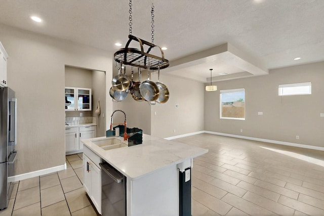 3406 Falkirk Rd NE, Rio Rancho, NM 87144 - kitchen featuring a sink, white cabinetry, an island with sink, baseboards, and a textured ceiling