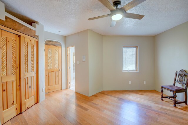 4700 Quaker Heights Pl NW, Albuquerque, NM 87120 - unfurnished room with light wood-style floors, a textured ceiling, a ceiling fan, and arched walkways