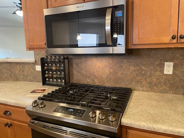 10912 Saltillo St NW, Albuquerque, NM 87114 - kitchen with appliances with stainless steel finishes, a ceiling fan, light countertops, and backsplash