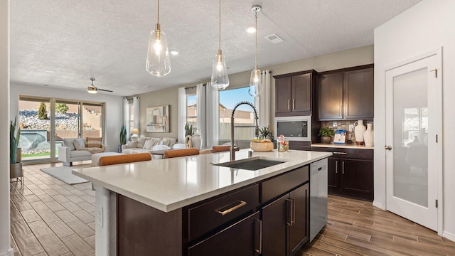4114 Silver Springs Rd NE, Rio Rancho, NM 87144 - kitchen featuring a sink, stainless steel appliances, a textured ceiling, dark brown cabinetry, and tasteful backsplash