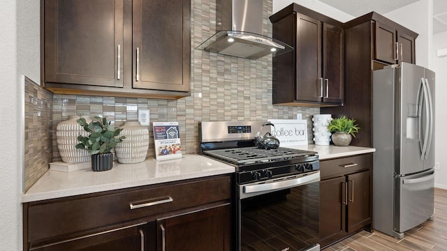 4114 Silver Springs Rd NE, Rio Rancho, NM 87144 - kitchen with appliances with stainless steel finishes, wall chimney range hood, dark brown cabinets, decorative backsplash, and light wood-type flooring