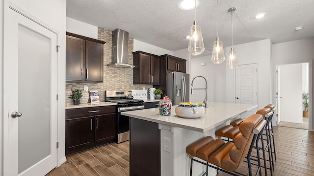 4114 Silver Springs Rd NE, Rio Rancho, NM 87144 - kitchen with stainless steel appliances, wall chimney exhaust hood, dark wood-style floors, a breakfast bar, and a center island with sink