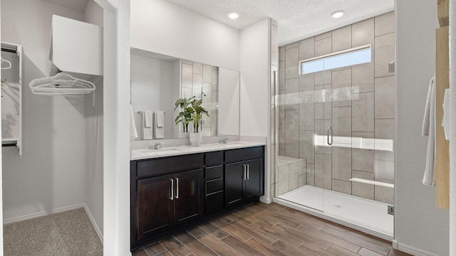 4114 Silver Springs Rd NE, Rio Rancho, NM 87144 - bathroom featuring a stall shower, baseboards, double vanity, wood finished floors, and a textured ceiling