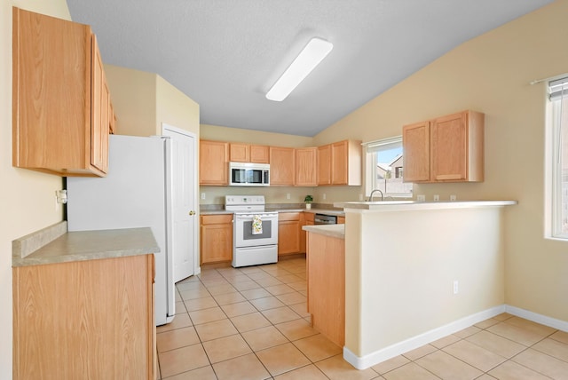 kitchen with stainless steel appliances, lofted ceiling, light brown cabinetry, light tile patterned floors, and light countertops