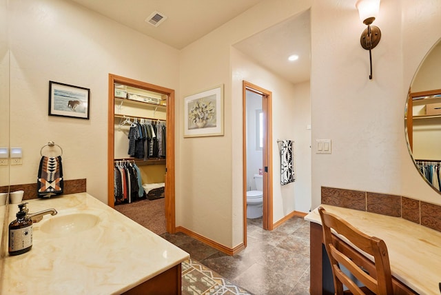 6119 La Paz Rd NE, Rio Rancho, NM 87144 - bathroom featuring vanity, toilet, a spacious closet, and baseboards