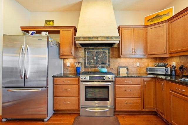 6119 La Paz Rd NE, Rio Rancho, NM 87144 - kitchen featuring stainless steel appliances, custom exhaust hood, brown cabinetry, wood finished floors, and tasteful backsplash