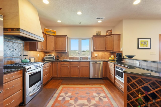 6119 La Paz Rd NE, Rio Rancho, NM 87144 - kitchen featuring stainless steel appliances, dark wood finished floors, brown cabinetry, recessed lighting, and a textured ceiling
