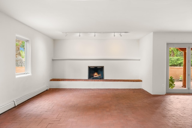 384 Chaparral Ln, Corrales, NM 87048 - unfurnished living room with baseboard heating, brick floors, track lighting, and plenty of natural light
