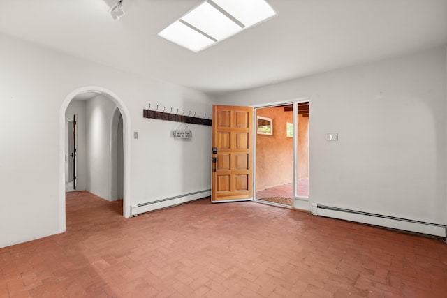 384 Chaparral Ln, Corrales, NM 87048 - spare room with a baseboard heating unit, arched walkways, and brick patterned floors