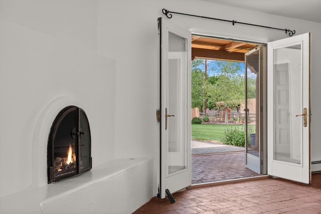 384 Chaparral Ln, Corrales, NM 87048 - entryway with brick floors, a warm lit fireplace, and a baseboard heating unit