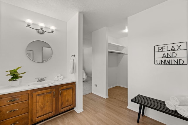 11 Riverside Rd, Peralta, NM 87042 - bathroom with vanity, wood finished floors, a spacious closet, baseboards, and a textured ceiling