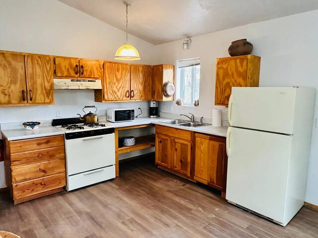 37 Lasso Ln, Pie Town, NM 87827 - kitchen with white appliances, under cabinet range hood, vaulted ceiling, wood finished floors, and brown cabinets