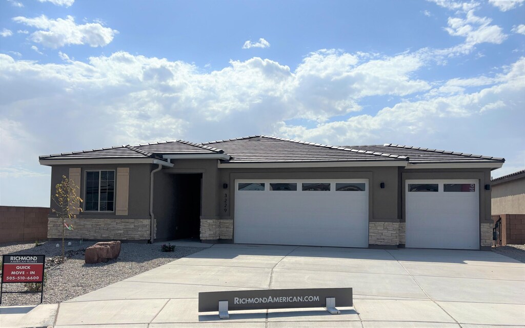 3229 Matador St SE, Rio Rancho, NM 87124 - prairie-style home with stone siding, a garage, driveway, a tile roof, and stucco siding