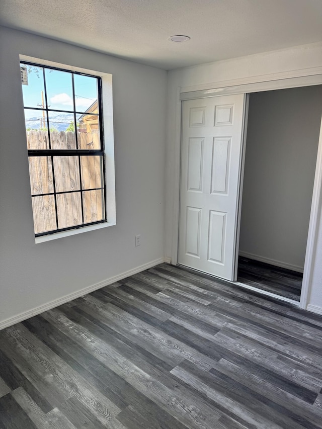 410 Utah St NE, Albuquerque, NM 87108 - unfurnished bedroom with dark wood-style flooring, a closet, and baseboards