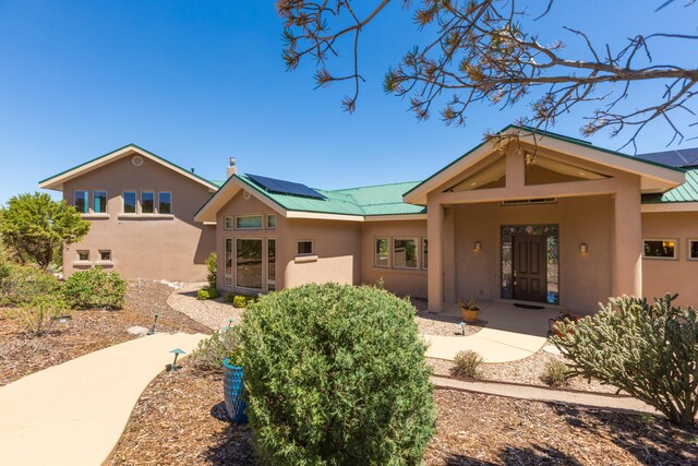 9 Canon Escondido, Sandia Park, NM 87047 - back of property featuring stucco siding, roof mounted solar panels, and metal roof
