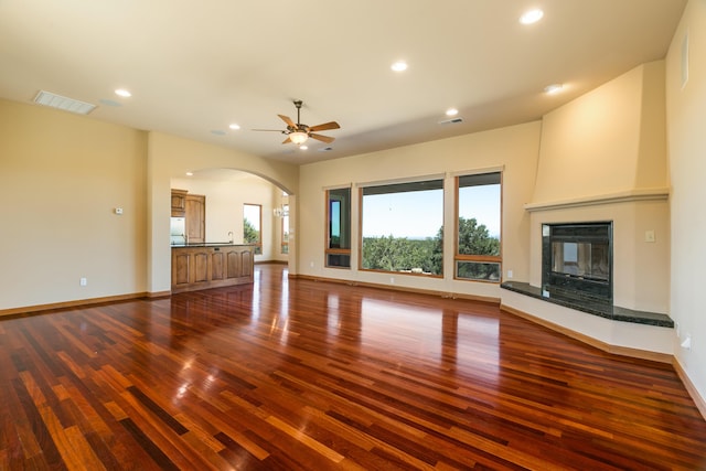 9 Canon Escondido, Sandia Park, NM 87047 - unfurnished living room featuring dark wood-type flooring, arched walkways, ceiling fan, recessed lighting, and a large fireplace