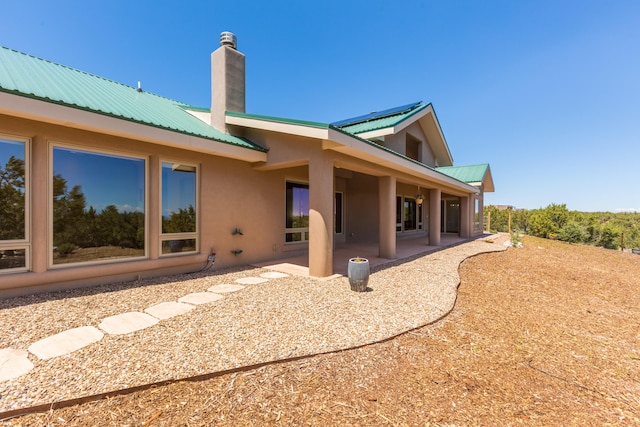 9 Canon Escondido, Sandia Park, NM 87047 - back of house featuring metal roof, stucco siding, a chimney, and a patio area