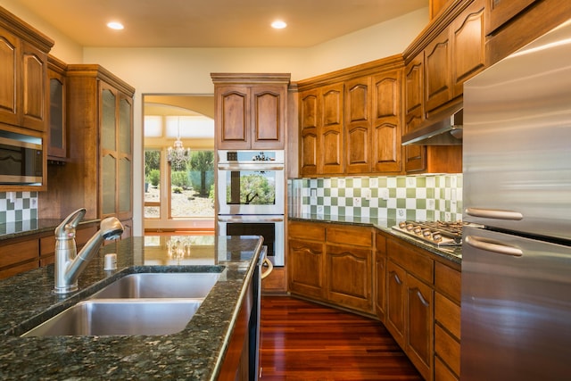 9 Canon Escondido, Sandia Park, NM 87047 - kitchen featuring stainless steel appliances, a sink, under cabinet range hood, dark stone counters, and dark wood-style flooring