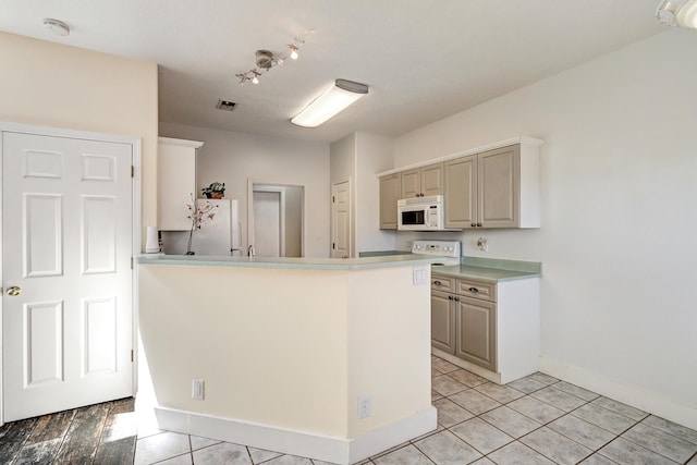 5209 Sugarbear Ct, Albuquerque, NM 87120 - kitchen featuring white appliances, track lighting, light tile patterned floors, baseboards, and a peninsula