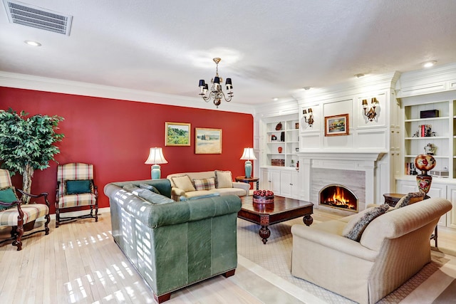 1513 Tinnin Rd NW, Los Ranchos, NM 87107 - living room featuring a chandelier, a warm lit fireplace, built in features, light wood finished floors, and crown molding