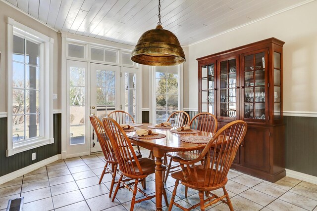 1513 Tinnin Rd NW, Los Ranchos, NM 87107 - dining area featuring healthy amount of natural light, light tile patterned flooring, ornamental molding, wainscoting, and wooden walls