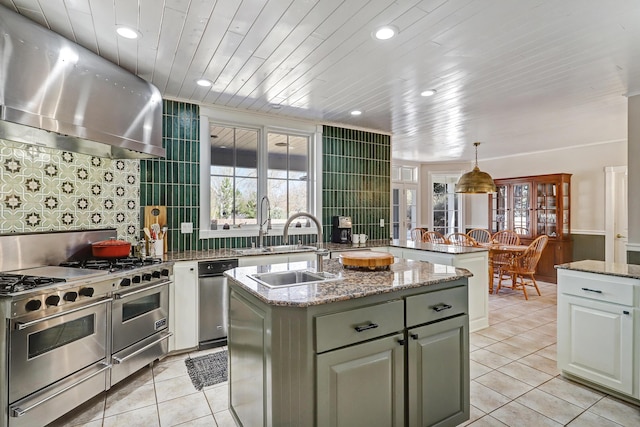 1513 Tinnin Rd NW, Los Ranchos, NM 87107 - kitchen featuring wall chimney exhaust hood, light tile patterned floors, an island with sink, recessed lighting, and decorative backsplash