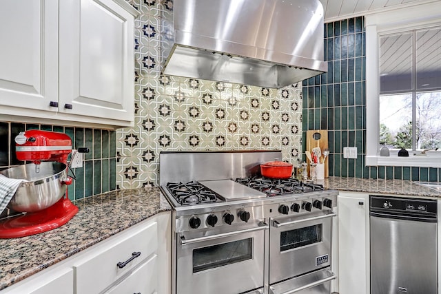 1513 Tinnin Rd NW, Los Ranchos, NM 87107 - kitchen featuring range with two ovens, wall chimney range hood, decorative backsplash, and white cabinets