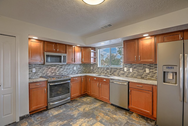 2308 Animas Ct NE, Rio Rancho, NM 87144 - kitchen with appliances with stainless steel finishes, a sink, backsplash, a textured ceiling, and brown cabinetry