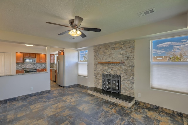 2308 Animas Ct NE, Rio Rancho, NM 87144 - unfurnished living room with ceiling fan, a fireplace, baseboards, and a textured ceiling