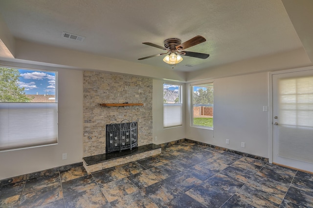2308 Animas Ct NE, Rio Rancho, NM 87144 - unfurnished living room with a large fireplace, healthy amount of natural light, a ceiling fan, baseboards, and a textured ceiling