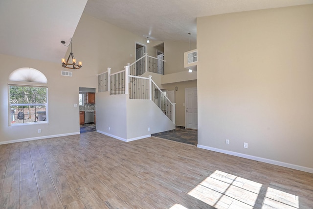 2308 Animas Ct NE, Rio Rancho, NM 87144 - unfurnished living room with high vaulted ceiling, a chandelier, stairway, baseboards, and wood finished floors