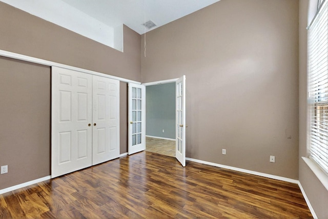 8720 Oakcrest Pl NW, Albuquerque, NM 87114 - unfurnished bedroom featuring wood finished floors, french doors, multiple windows, and a towering ceiling