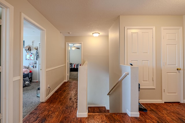 10500 Trieste Ct NW, Albuquerque, NM 87114 - hallway featuring an upstairs landing, dark wood-type flooring, a textured ceiling, and baseboards