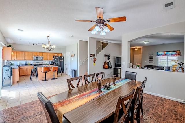 10500 Trieste Ct NW, Albuquerque, NM 87114 - dining room with a ceiling fan, arched walkways, a chandelier, a textured ceiling, and baseboards