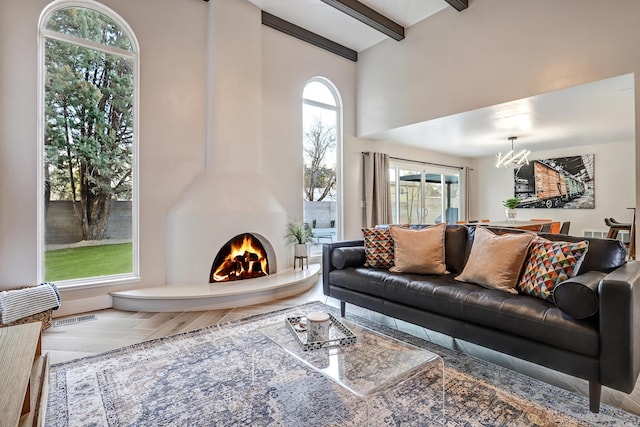 6507 Loftus Ave NE, Albuquerque, NM 87109 - living area with a chandelier, beamed ceiling, a warm lit fireplace, and a towering ceiling