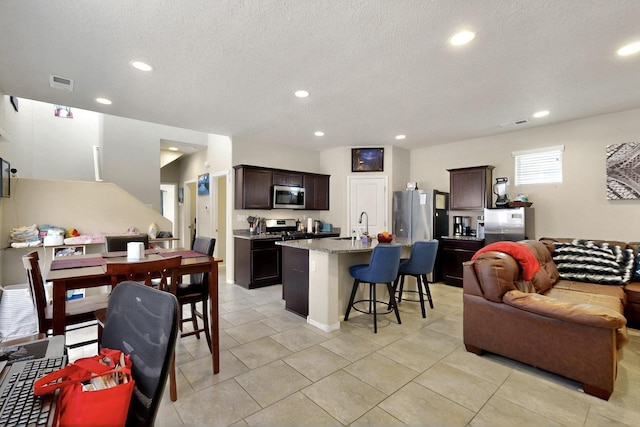 3136 Morrissey St SW, Albuquerque, NM 87121 - kitchen with appliances with stainless steel finishes, open floor plan, a breakfast bar area, recessed lighting, and dark brown cabinetry