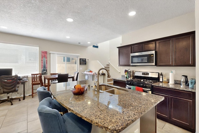 3136 Morrissey St SW, Albuquerque, NM 87121 - kitchen featuring appliances with stainless steel finishes, a sink, stone countertops, light tile patterned flooring, and an island with sink