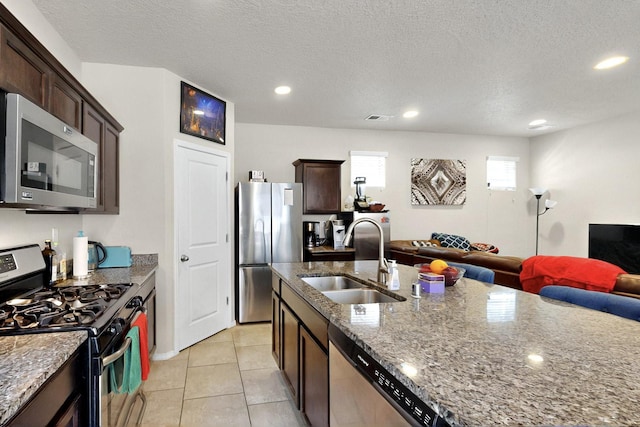 3136 Morrissey St SW, Albuquerque, NM 87121 - kitchen featuring appliances with stainless steel finishes, a sink, open floor plan, stone countertops, and dark brown cabinetry