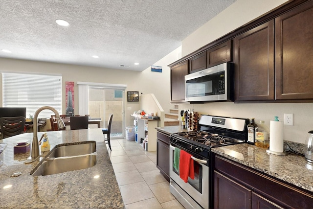 3136 Morrissey St SW, Albuquerque, NM 87121 - kitchen with appliances with stainless steel finishes, a sink, dark brown cabinetry, light tile patterned flooring, and dark stone counters