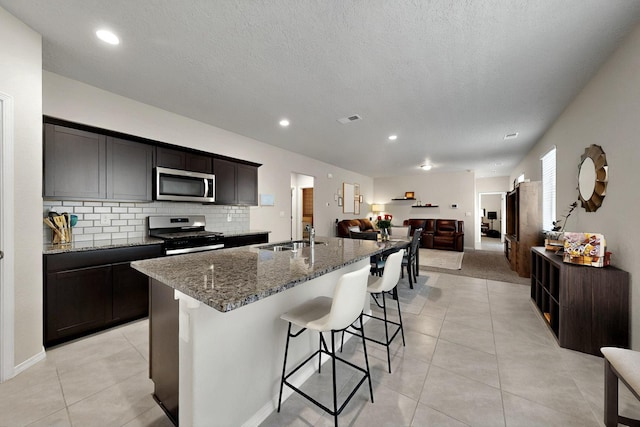 3179 Kunzita St SE, Rio Rancho, NM 87124 - kitchen featuring appliances with stainless steel finishes, a sink, open floor plan, light tile patterned floors, and dark stone counters