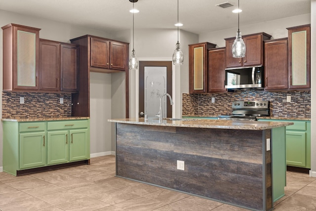 4909 Calle Espana NW, Albuquerque, NM 87120 - kitchen featuring appliances with stainless steel finishes, tasteful backsplash, a kitchen island with sink, recessed lighting, and light stone countertops