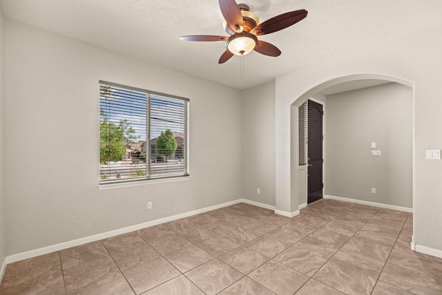 4909 Calle Espana NW, Albuquerque, NM 87120 - unfurnished room featuring arched walkways, ceiling fan, a textured ceiling, light tile patterned floors, and baseboards