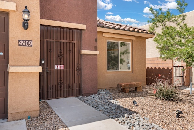 4909 Calle Espana NW, Albuquerque, NM 87120 - doorway to property featuring fence, a gate, stucco siding, and a tile roof