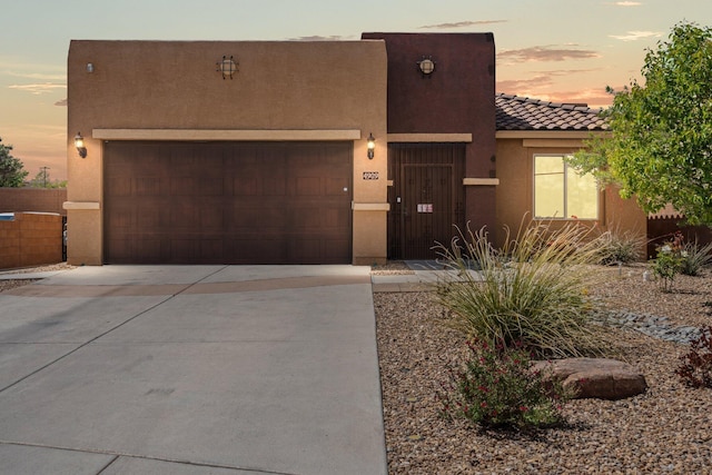 4909 Calle Espana NW, Albuquerque, NM 87120 - pueblo-style home with stucco siding, driveway, a tile roof, and an attached garage