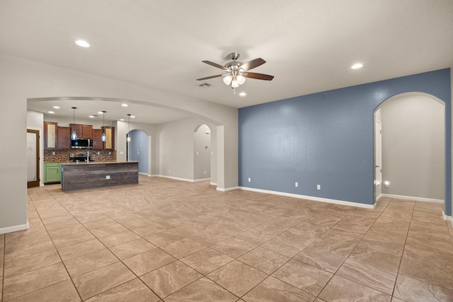 4909 Calle Espana NW, Albuquerque, NM 87120 - unfurnished living room featuring arched walkways, ceiling fan, recessed lighting, light tile patterned floors, and baseboards